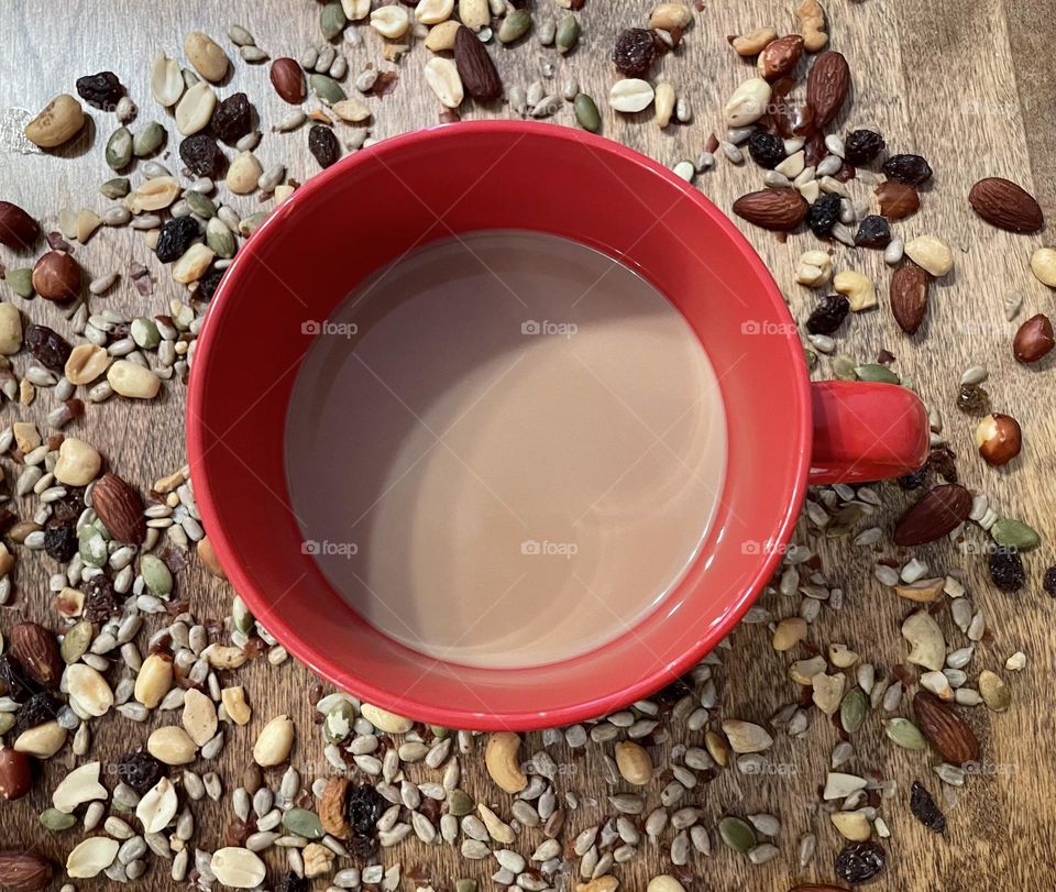 One perfect circle, the top of this red coffee mug,surrounded with some circular , and oval nuts, seeds and raisins, taken with my iPhone 12.