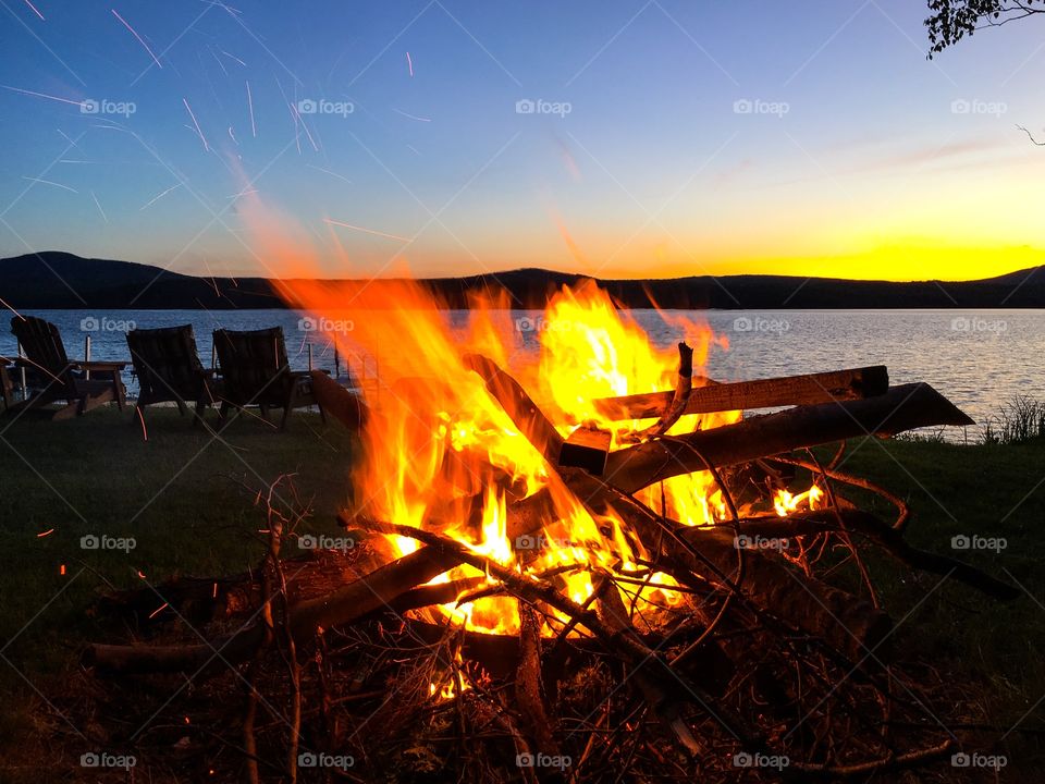 Huge campfire by the lake in New York States Adirondack mountains, at sunset. This is Chateauguay lake 