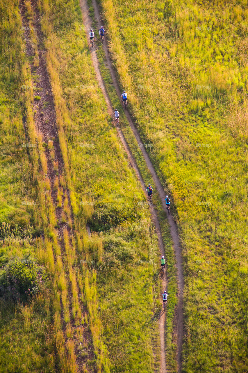 Relaxing on the road having fun with friends in the field - image of mountain bikers on dirt road from above