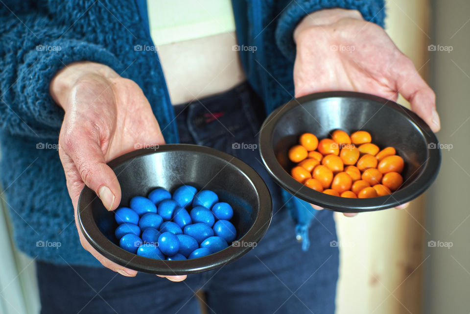 Hands holding plates with orange and blue sweets