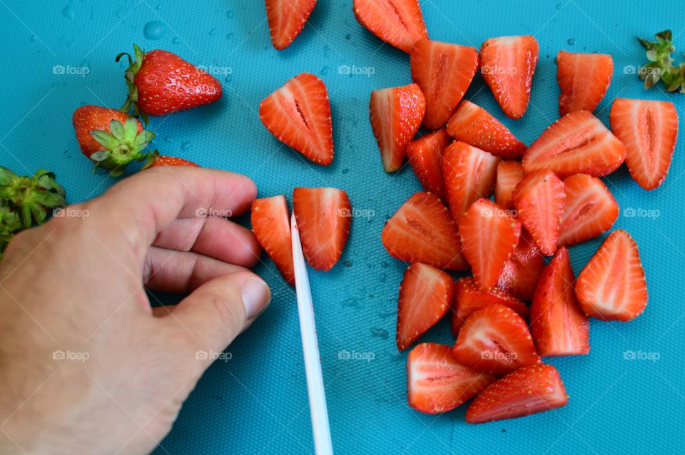 Cutting stawberries on a colored cutting board