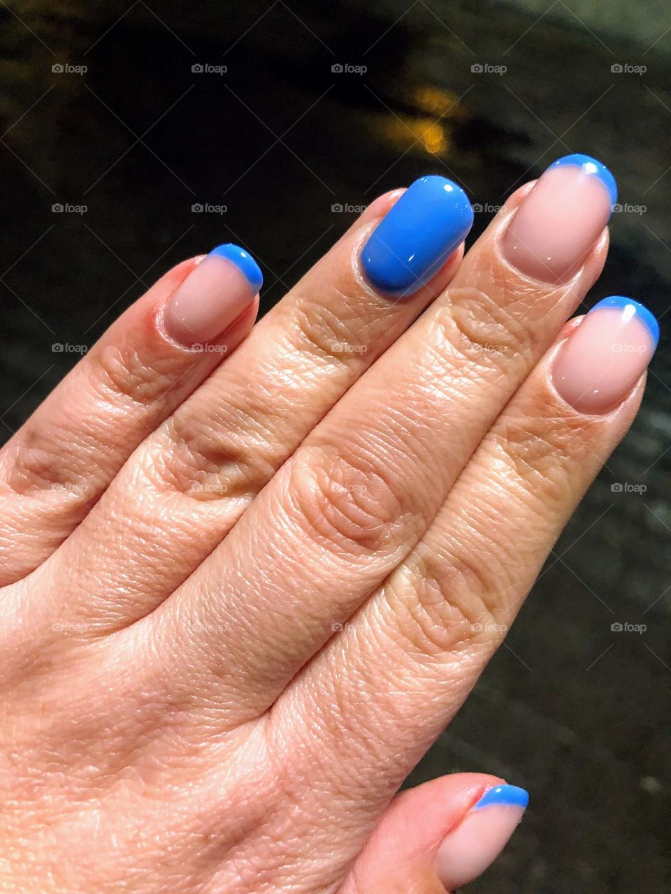 Pretty asymmetrical french manicure with blue and clear transparent nail polish