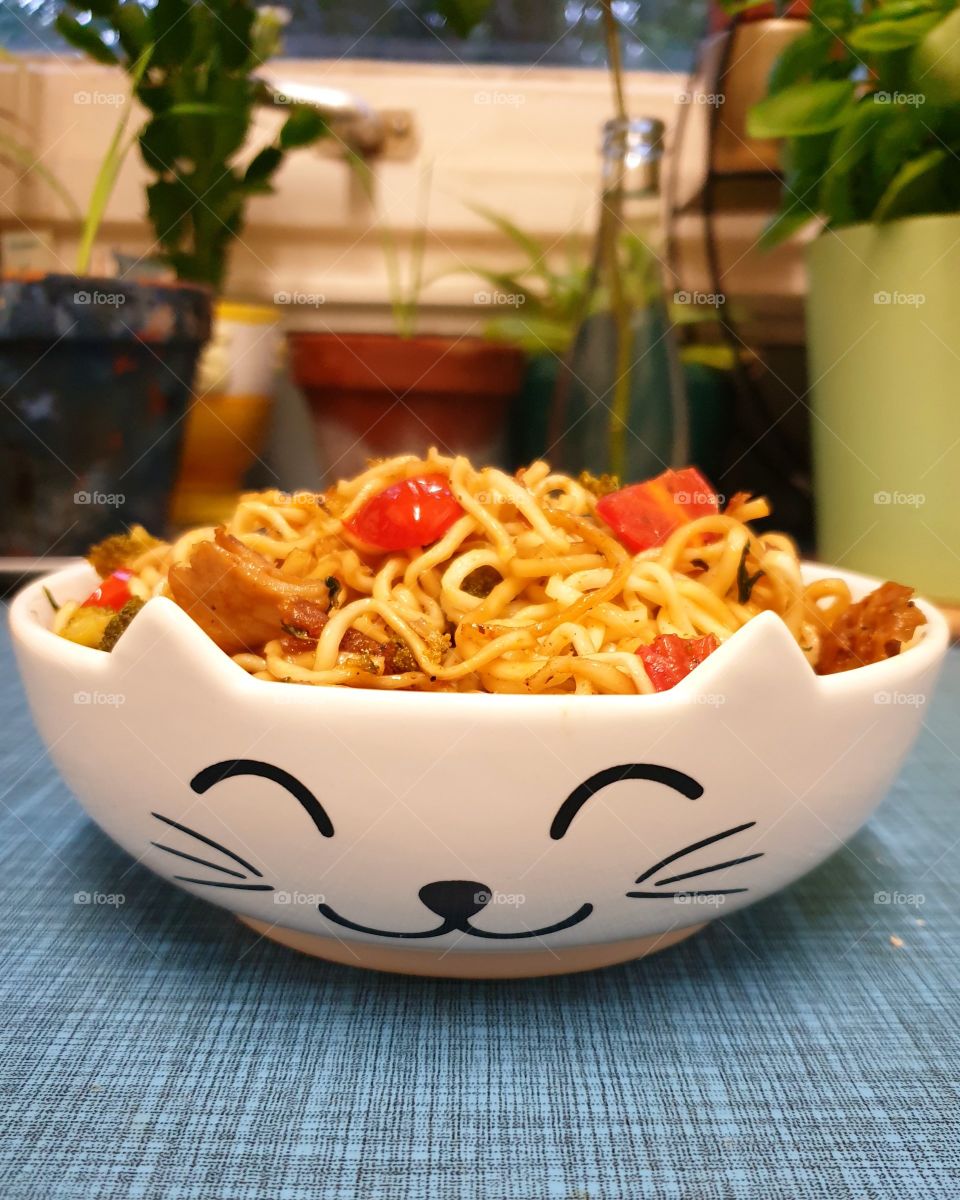 Fried noodles in a cute bowl with cat ears and a cat face.