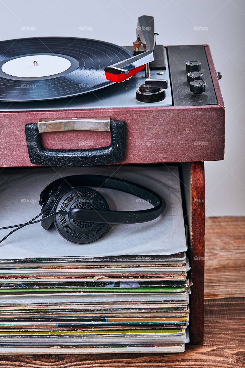 Stack of black vinyl records, turntable vinyl player and headphones. Classic stereo set. Candid people, real moments, authentic situations