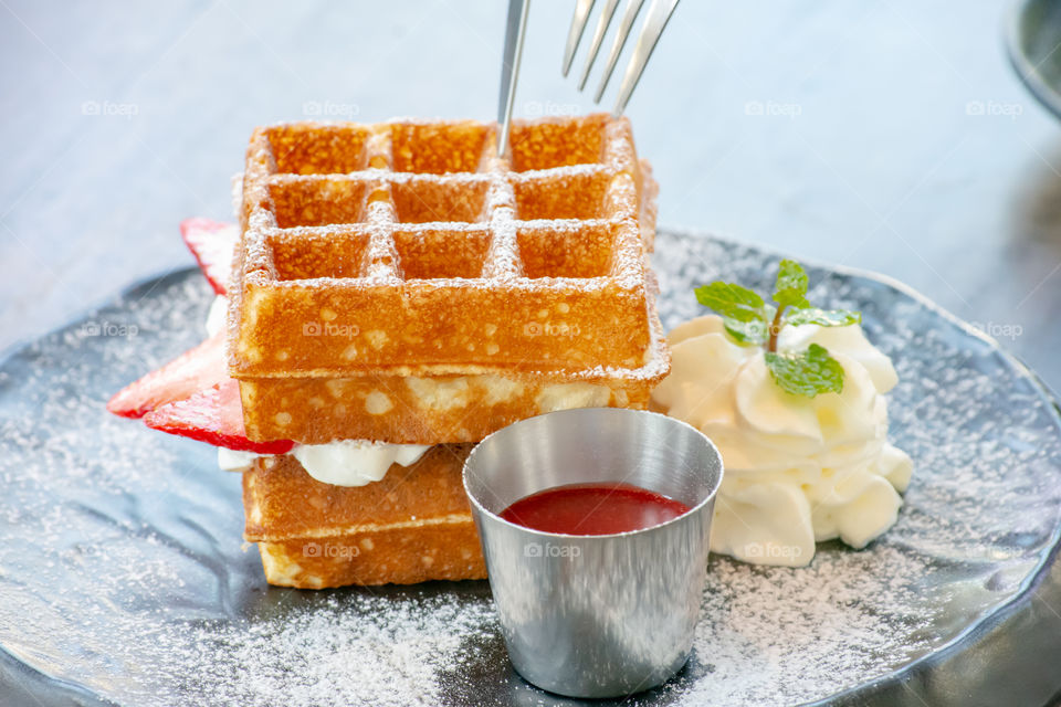 Waffle Strawerry fresh cream in the black plate on wooden table.