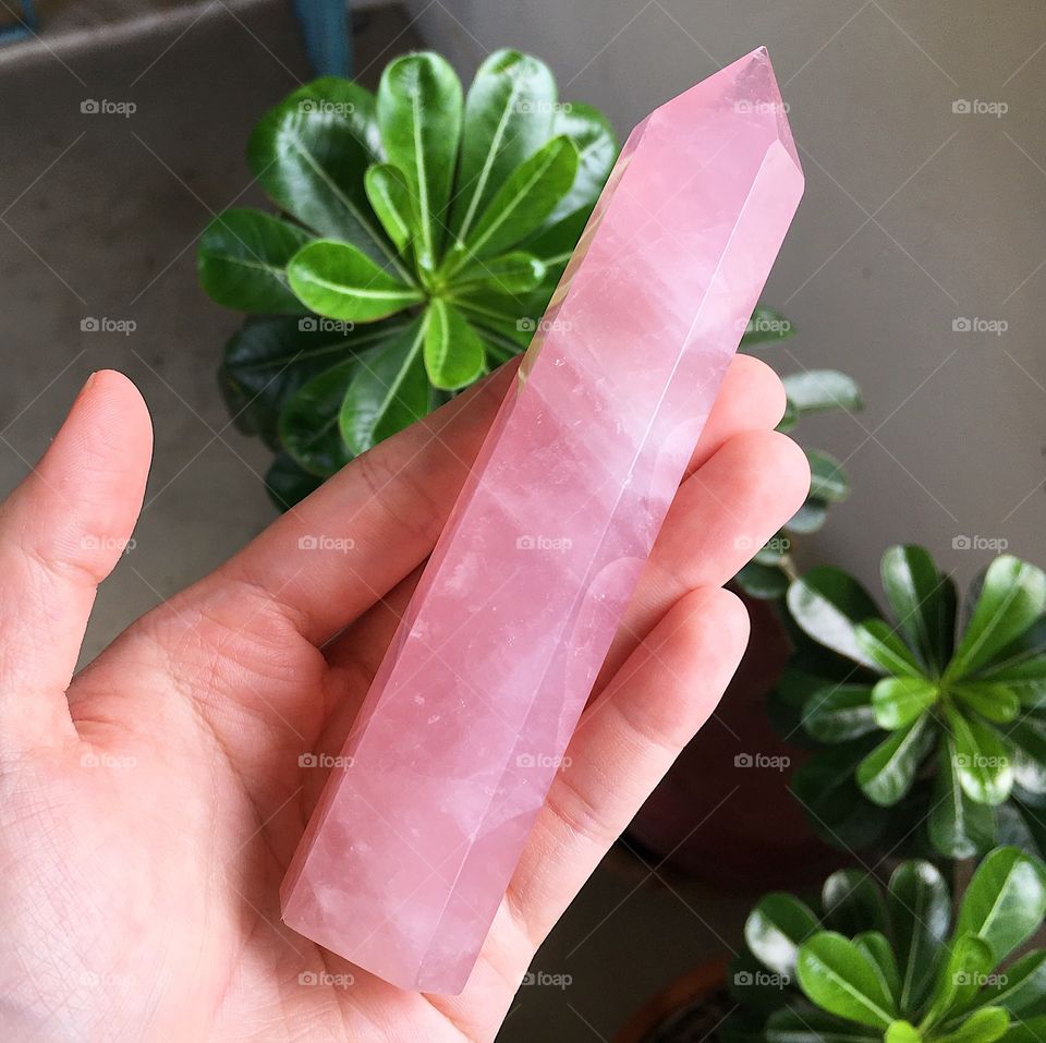 A polished rose quartz crystal tower point.