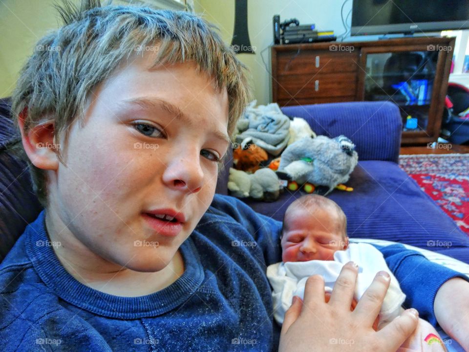 Young Boy Holding His Newborn Baby Sister
