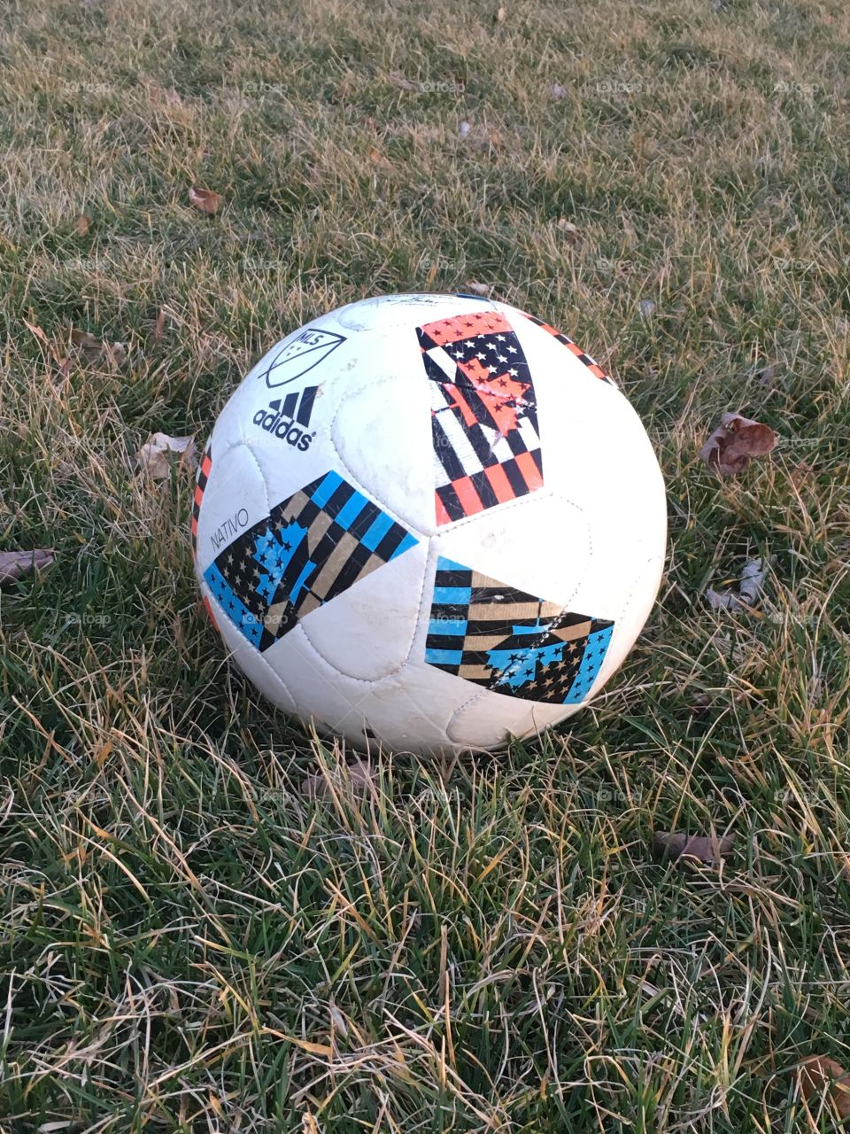 A worn, used soccer ball resting on grass.