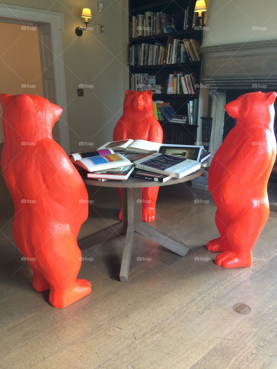 Artist installation of red recycled plastic bears studying art books in a museum library 