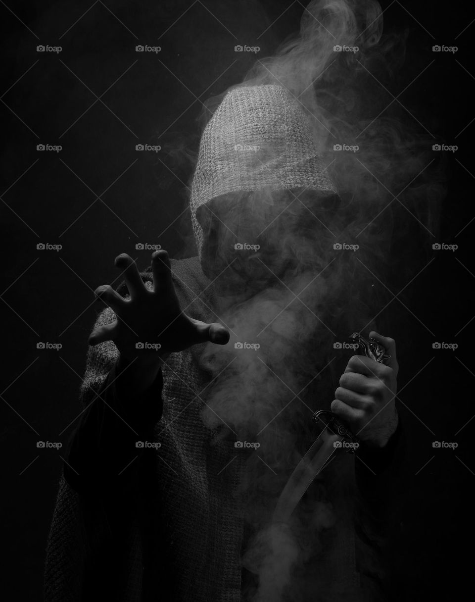 A man with a knife in the smoke and darkness
