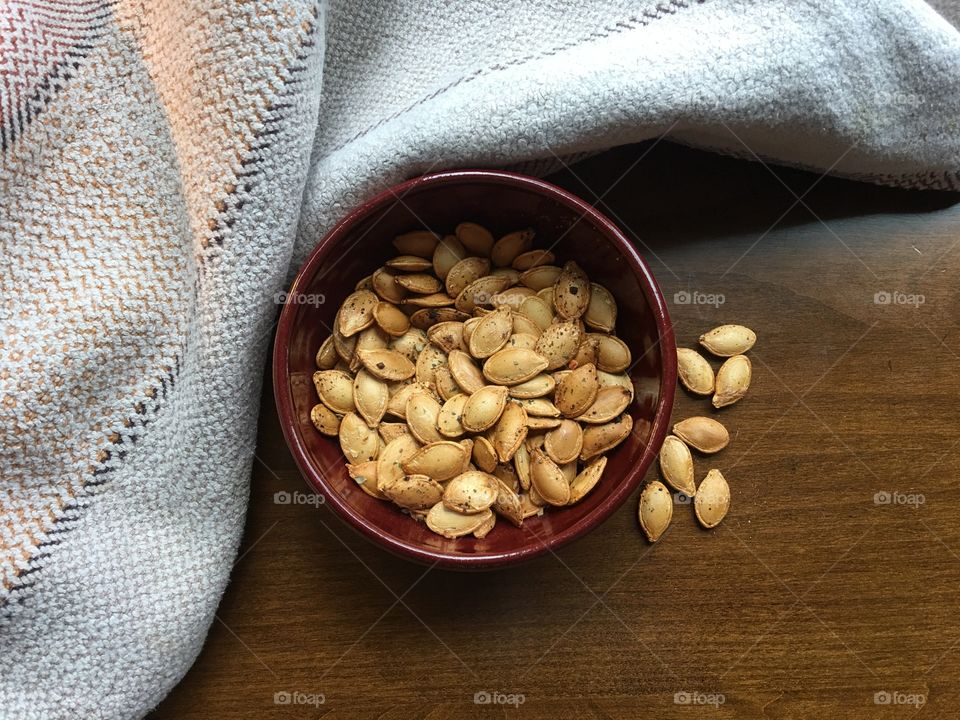 Roasted pumpkin seeds snack flat lay with handwoven towel and handmade pottery bowl