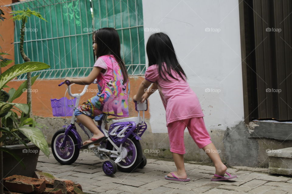 two litlle girls ride a bike