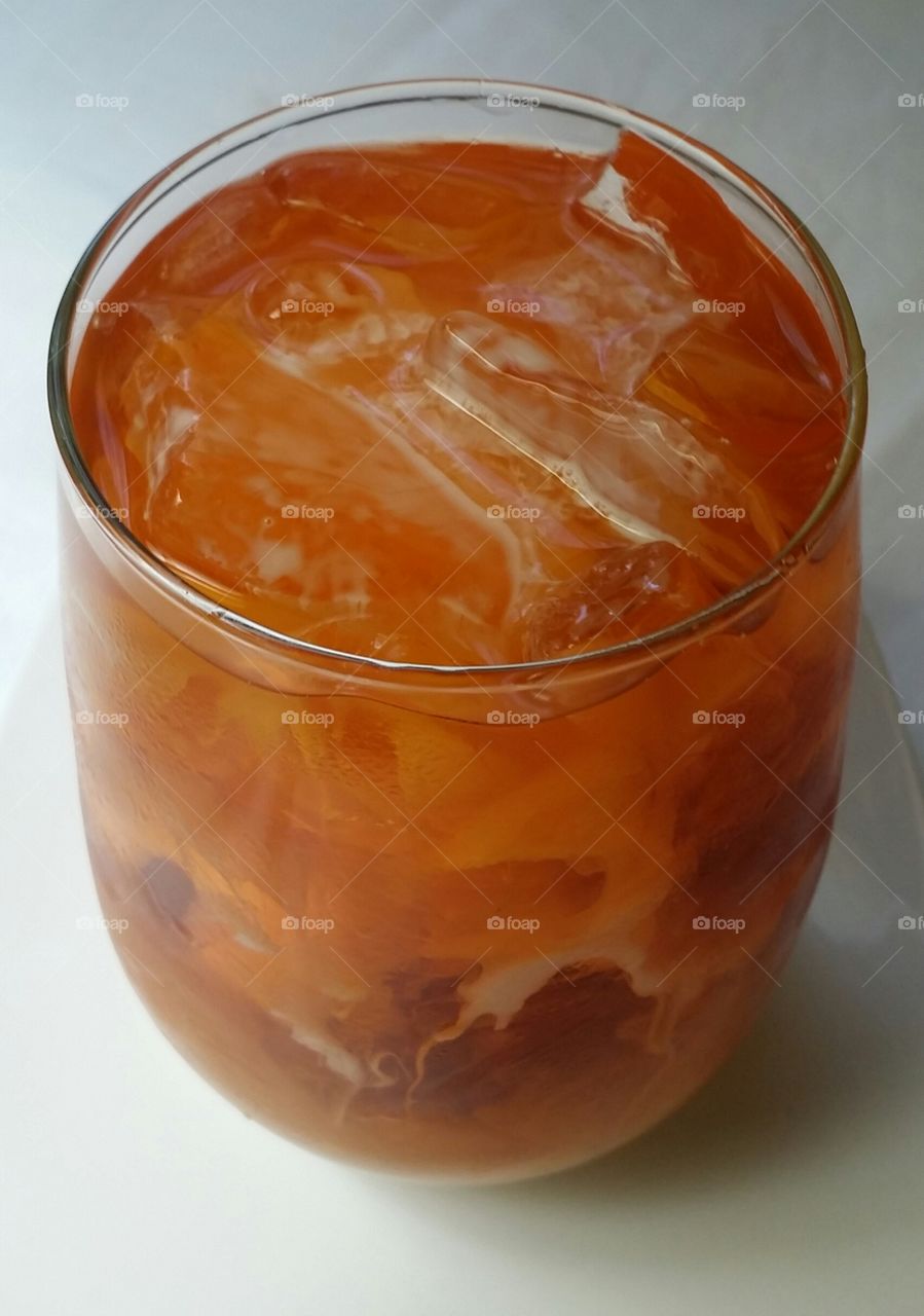 A glass of sweet Thai iced tea topped with creamy milk