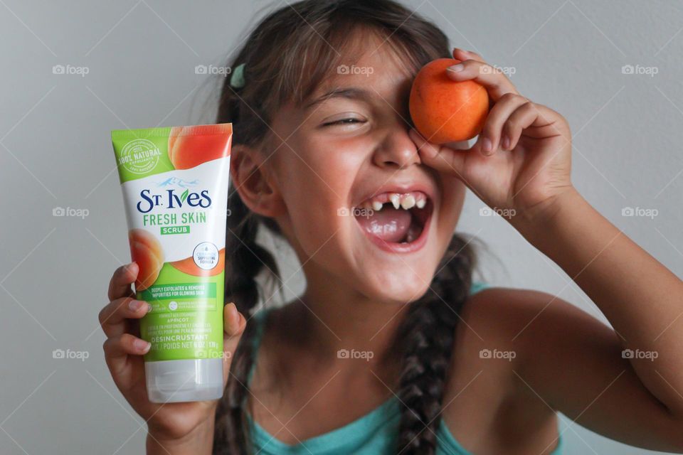 Cute happy little girl with St.Ives apricot scrub and apricot fruit