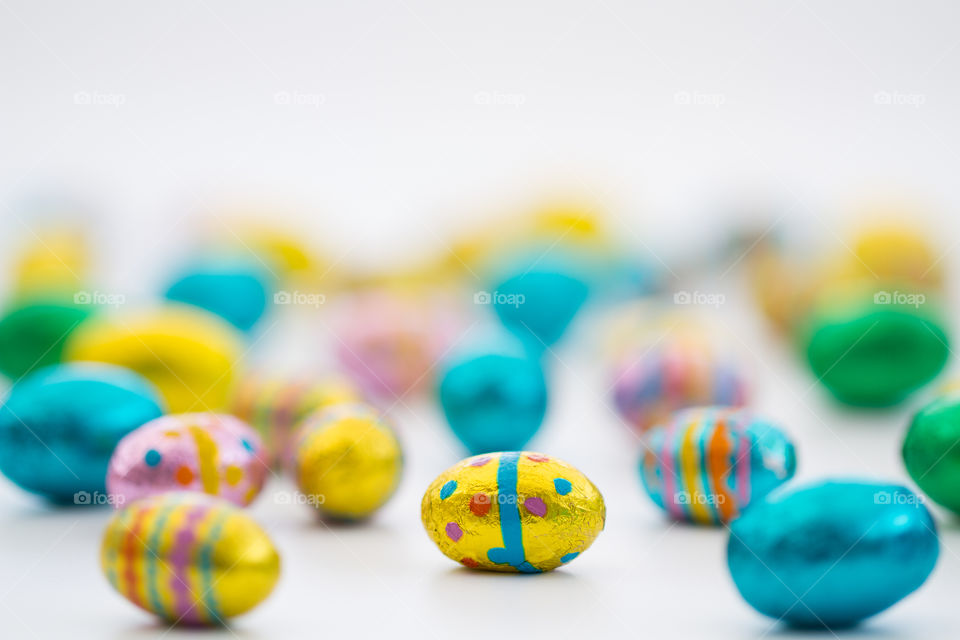 Lots of little chocolate Easter eggs on a white background. Colourful Easter eggs.