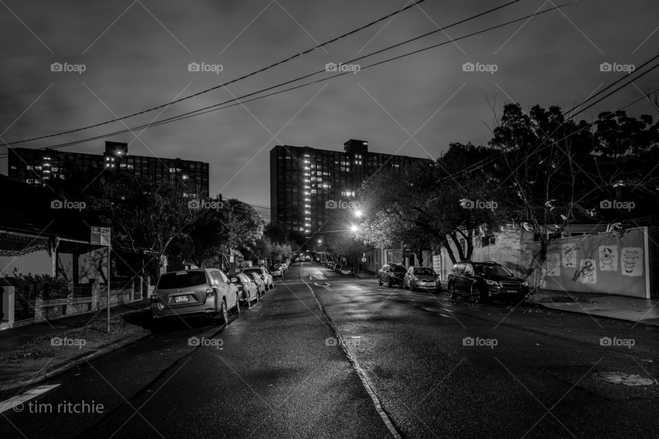 Zamia St in Sydney’s Redfern. You can just spot the skipping girl art on the corrugated iron on the right, the road glistens with predawn rain and the monoliths of public housing at the end of the road act as imposing comments on humanity