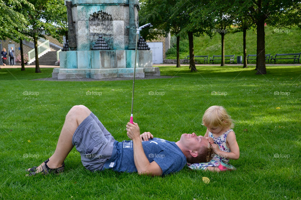 Father and daughter in park taking selfie with stick