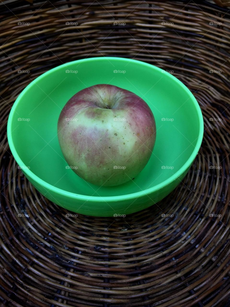 An apple inside the plastic neon green bowl