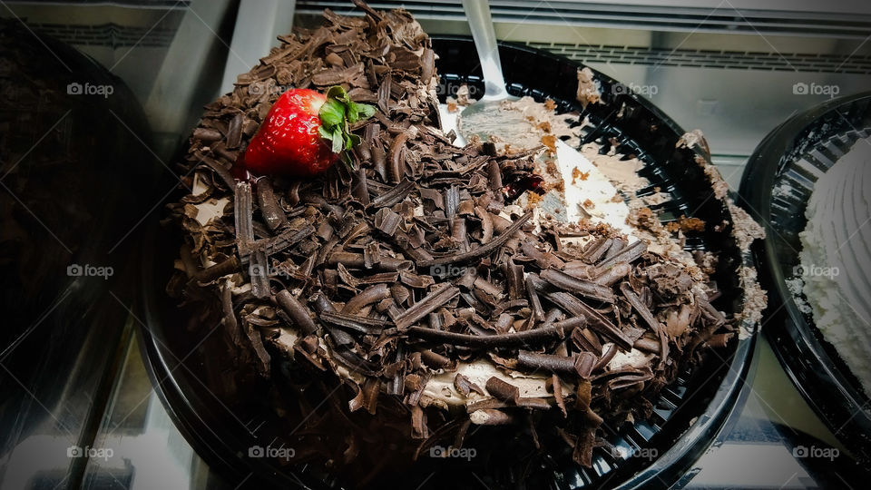 Confeitaria, bolo delicioso com recheios doces e coberturas de chocolate escuro e morangos.