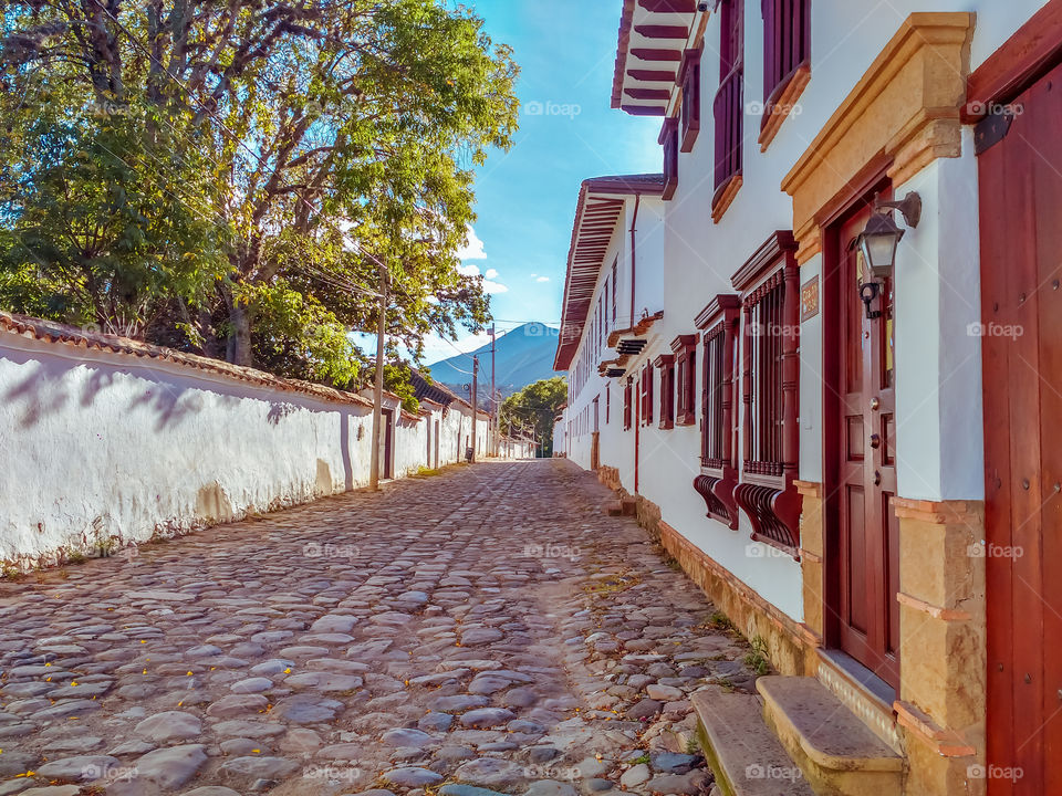 Calle de Villa de Leyva, Boyacá, Colombia en una mañana soleada y con cielo azul. Fachadas de casas, arquitectura colonial. Villa de Leyva street, Boyacá, Colombia on a sunny morning with blue sky.  Facades of houses, colonial architecture.