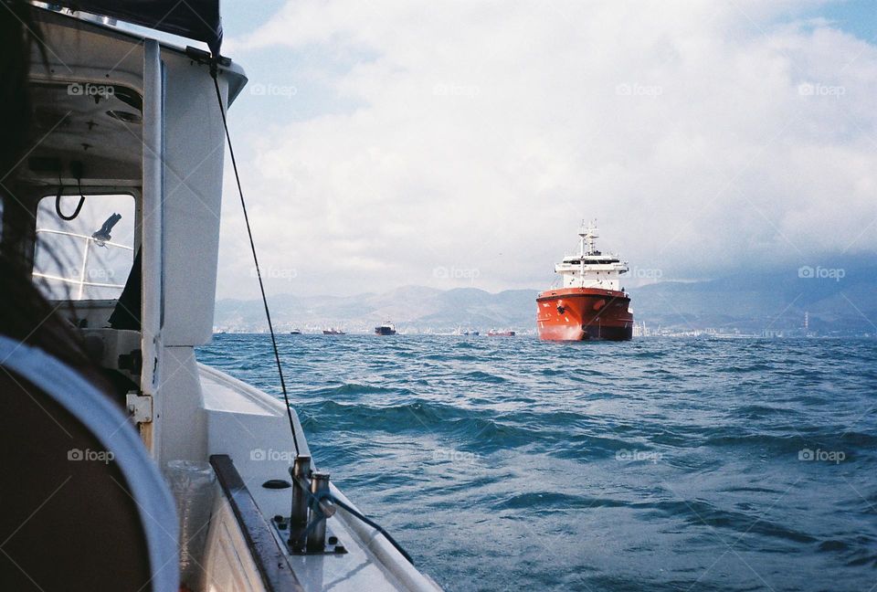 Red ship at the Black Sea, blue water, yacht, white boat, cloudy day