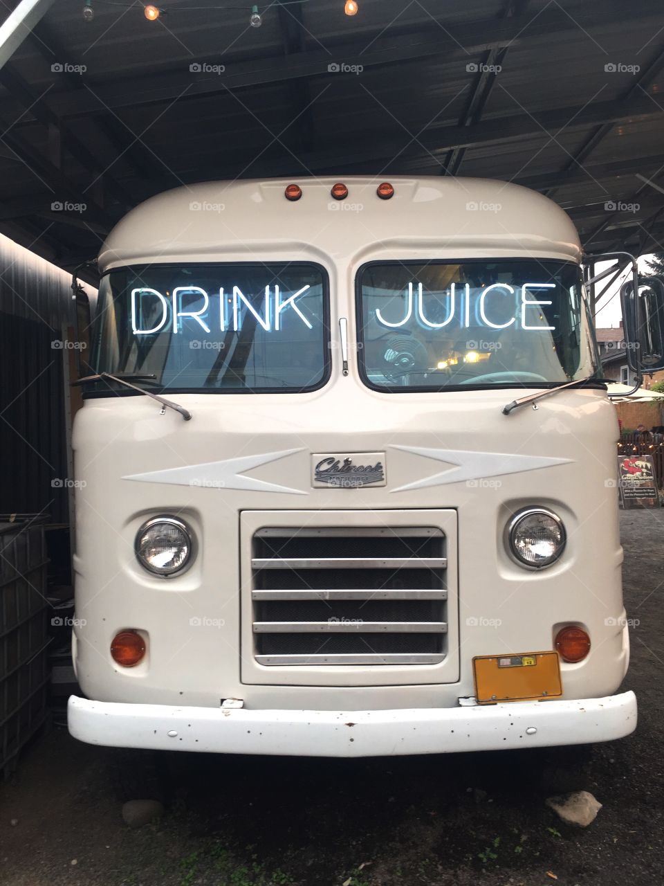 The front of a parked vintage Chinook motor home with ‘Drink Juice’ neon sign in the windshield