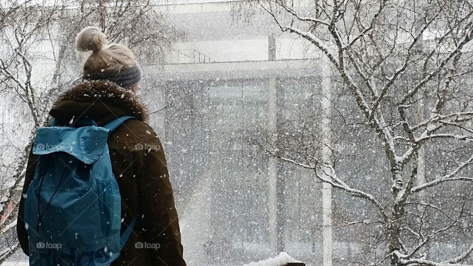 lady with blue backpack and heavy snow