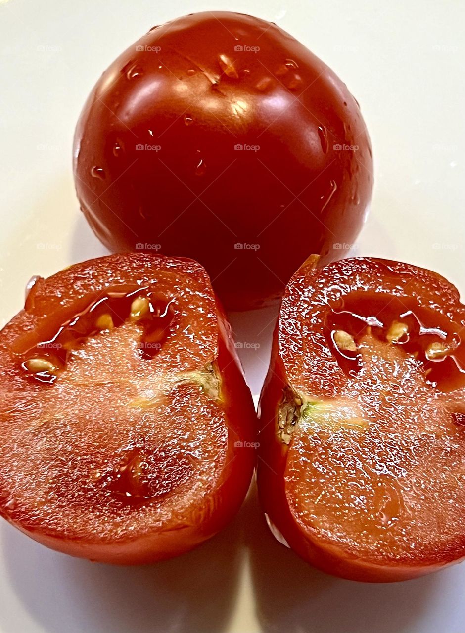 The photo shows two tomatoes. One whole, the second cut in half. 