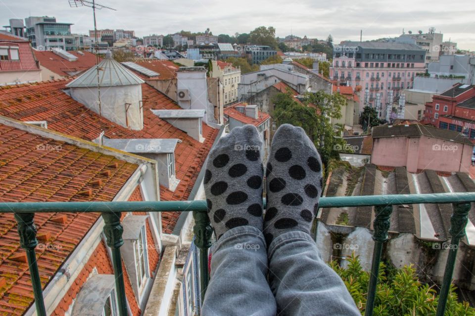 Person's leg in socks against Lisbon cityscape