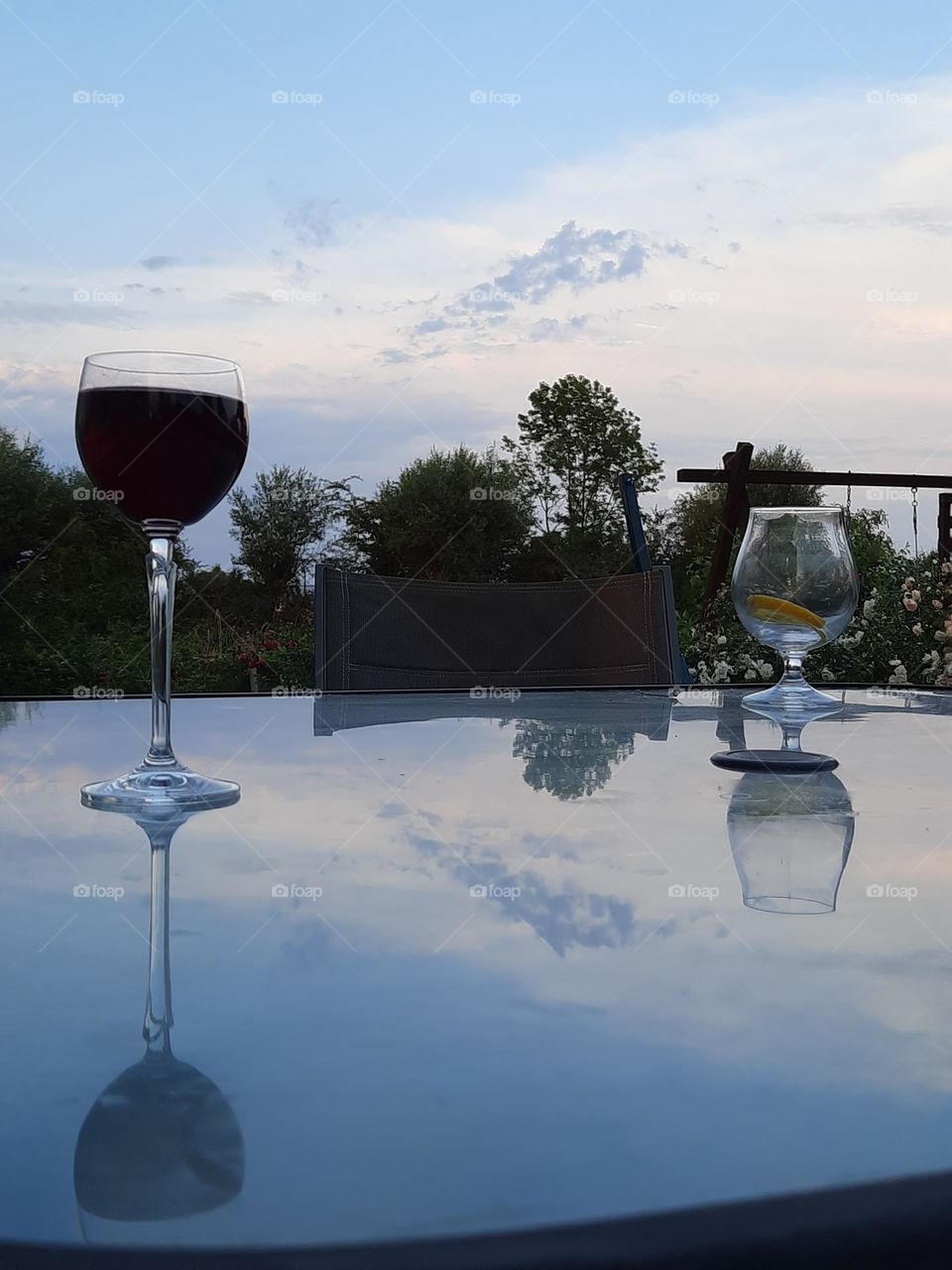 glasses trees and sky reflected in glass table