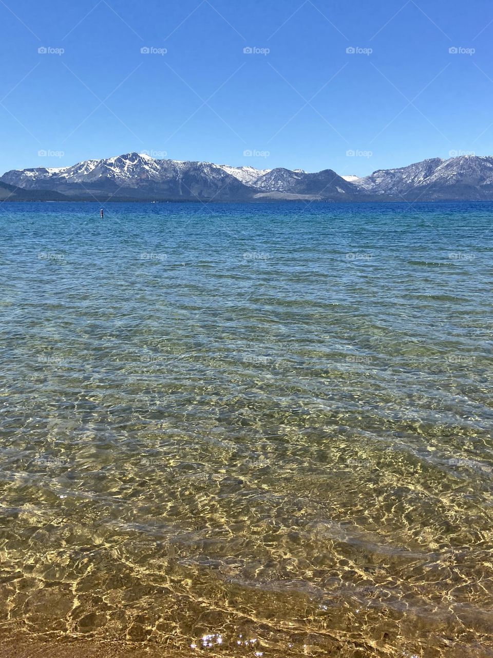 Clear glacier melt lake with mountains