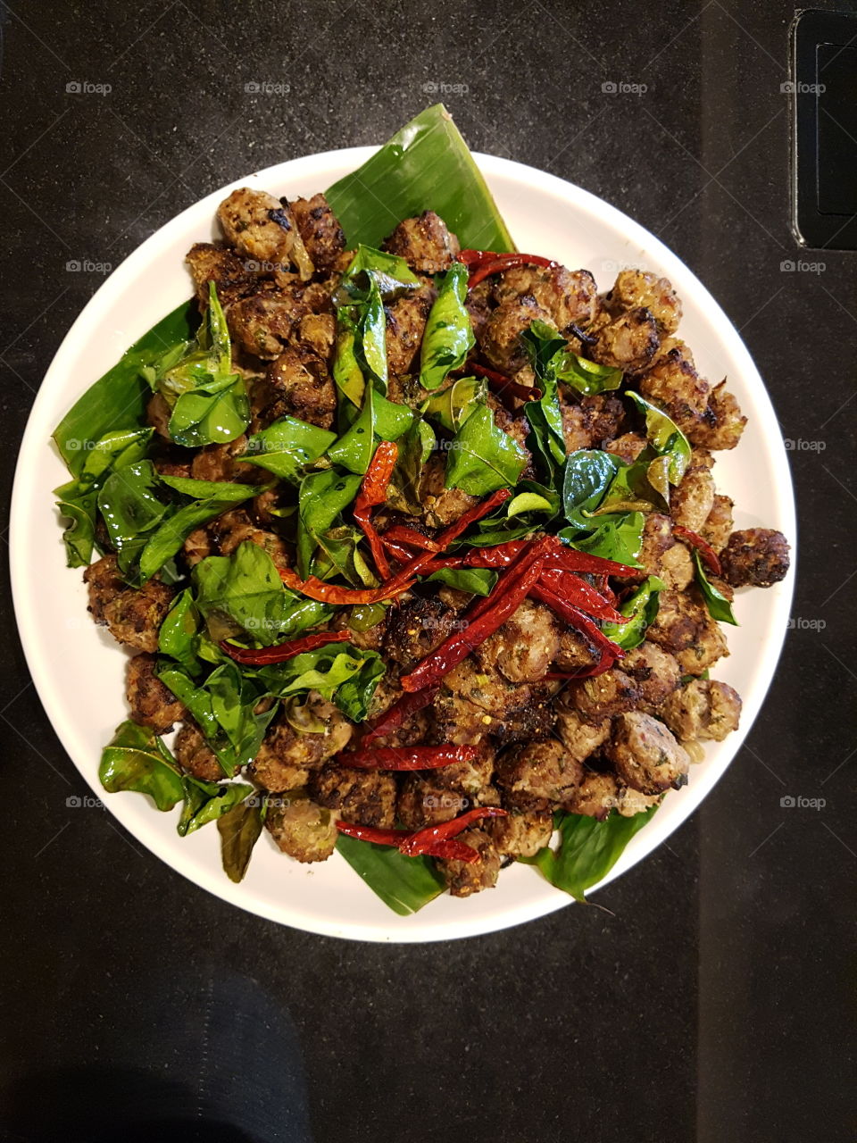 close up of Thai food speciality deep fried minced meat with chillies and kafgir lime leaves served on a plate, flat lay view