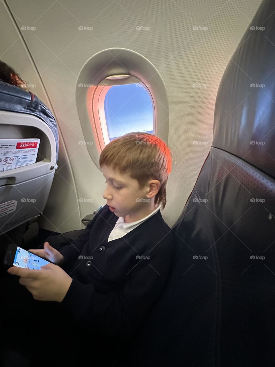Boy sitting in fly near the window 