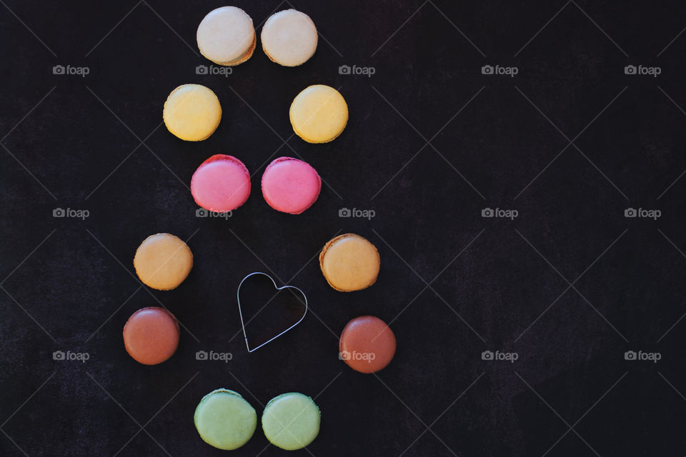 Background of the colorful delicious macaroons at dark table close up. Womans day. Greetings card. Flat lay.