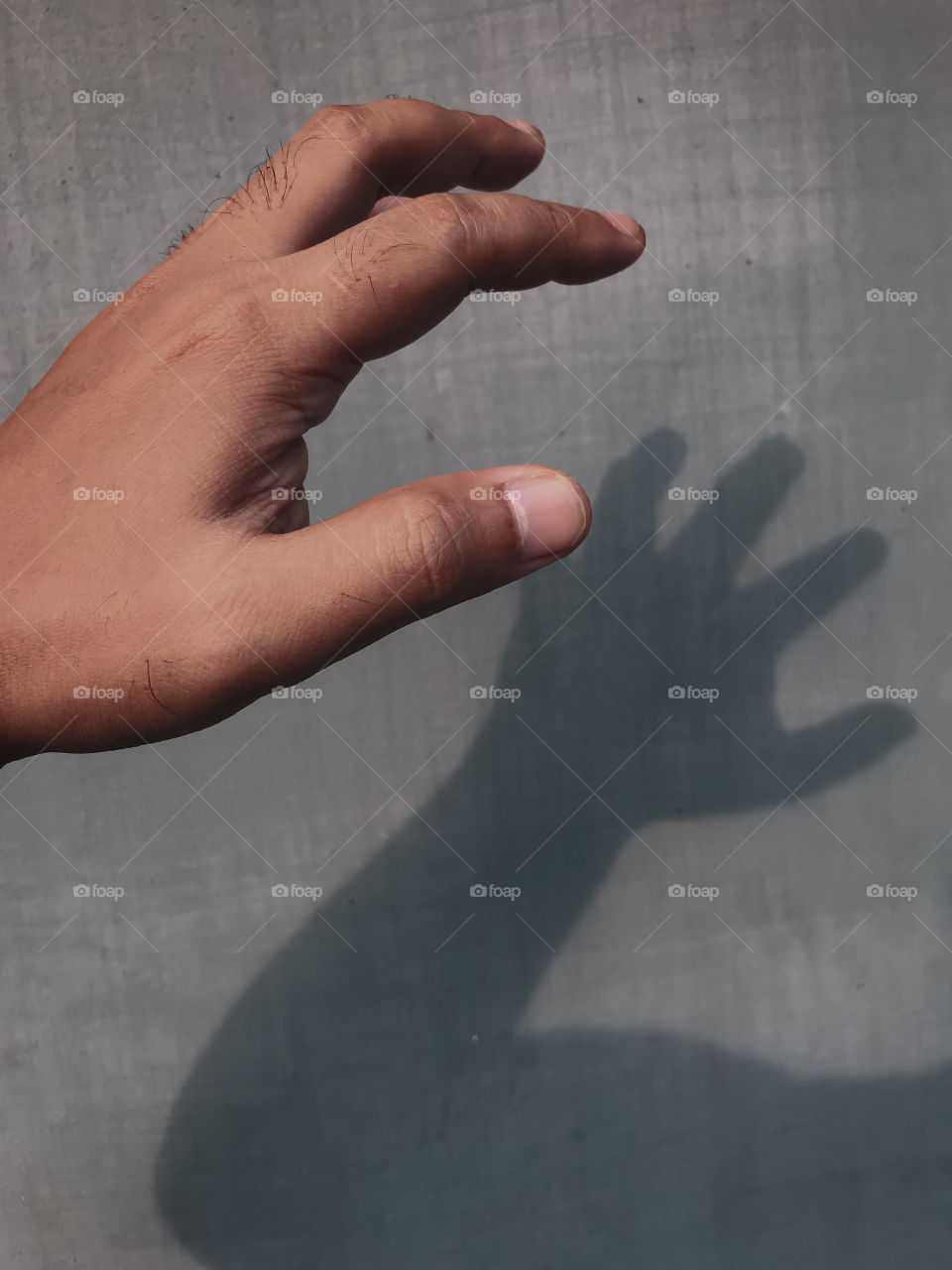 A man having fun with his own shadows of his hand and body, afternoon time close to sunset time