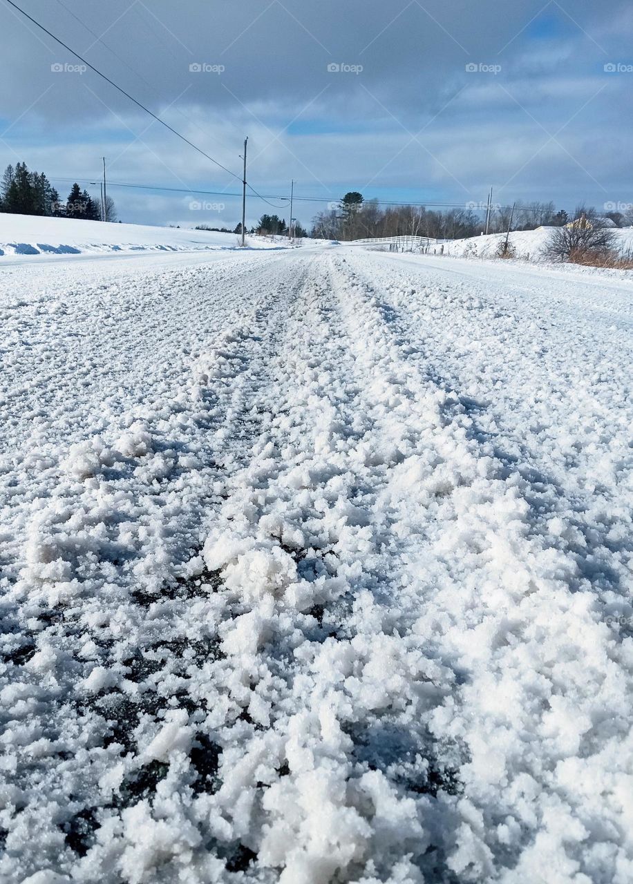 Tire tracks on a snow covered road after a storm during winter in New England 2022.