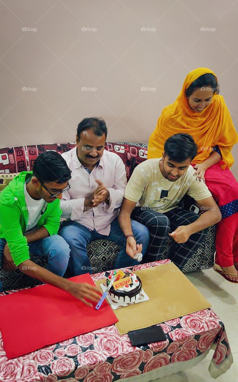 Indian Family enjoying birthday celebration and cutting cake at home