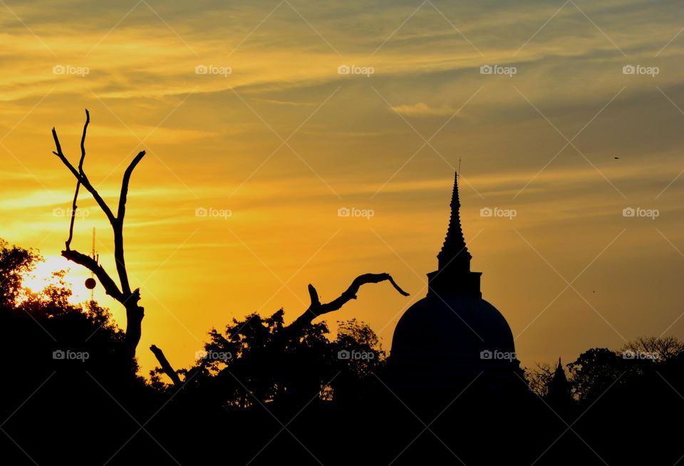 Tranquil Reverie: Sunset Silhouette of a Sacred Pagoda in Thanthirimale, Sri Lanka
