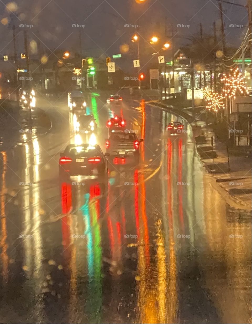 Driving on a rainy evening with all the lights reflecting on the pavement 