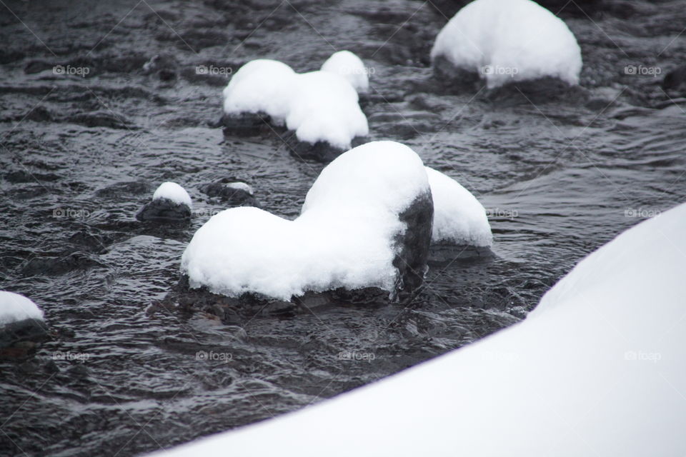 Freezing cold river with a stone heart covered in snow 