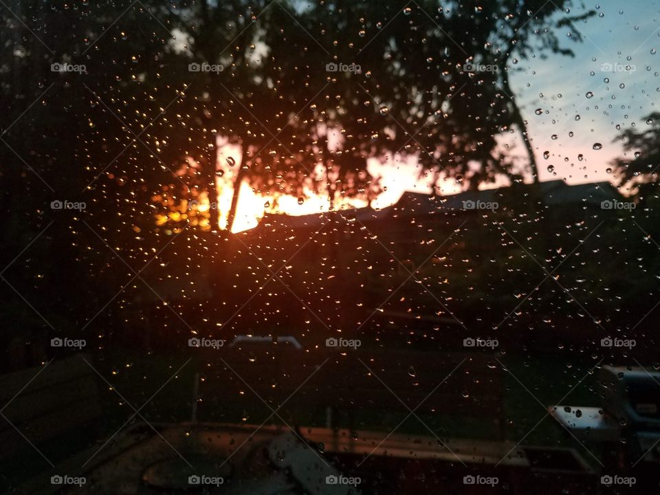 Photo taken through a window with rain drops on it at sunset