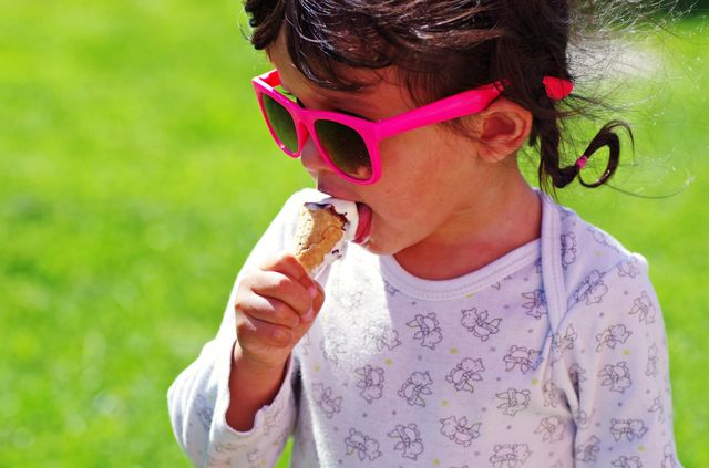 The small kid eating ice cream at the summer time.