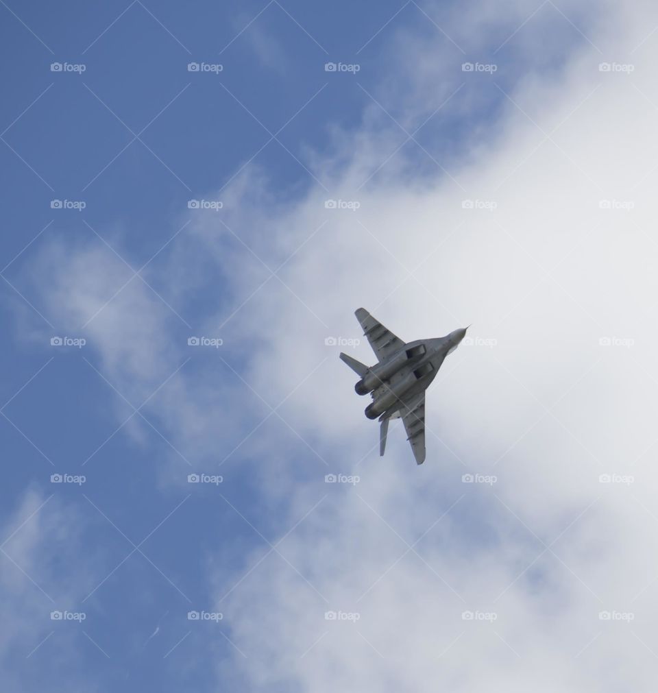 The plane is flying against the blue sky. Aerobatic figure, military aircraft.