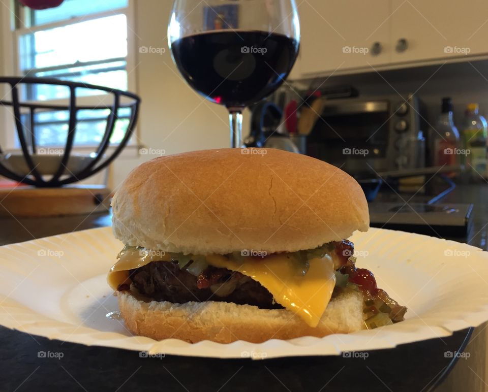 Cheeseburger on a paper plate with a glass of red wine. Why not? 