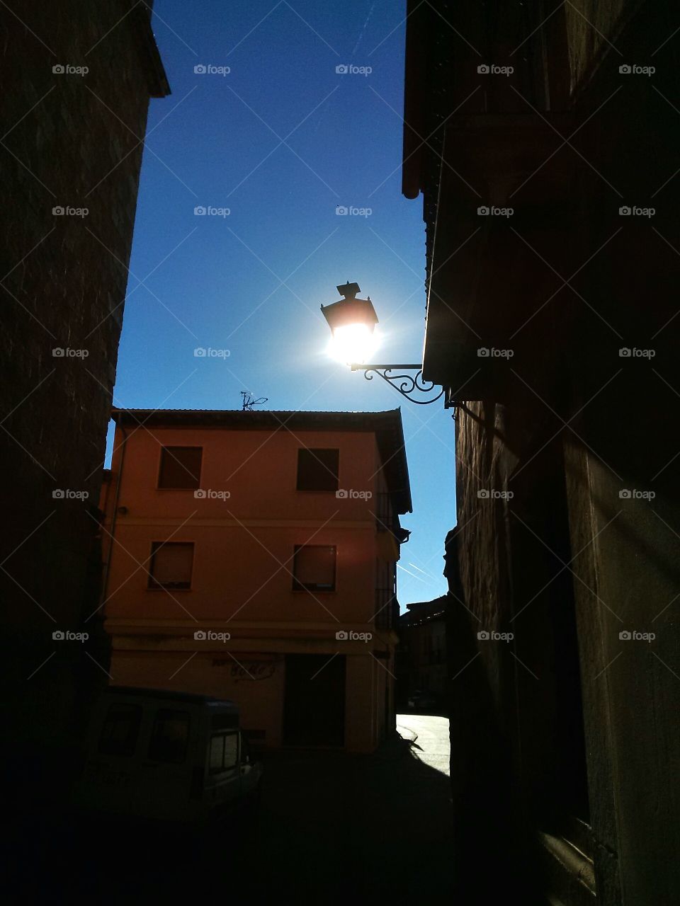 Bright sunlight behind a street lamp in a village.
