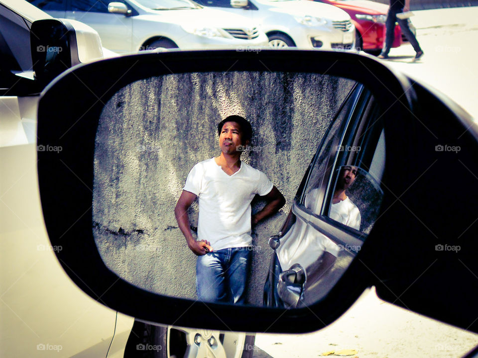 asian men reflected through a car's side mirror