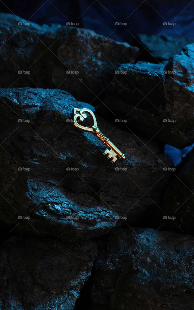 Antique golden key on dark night stone rock texture background