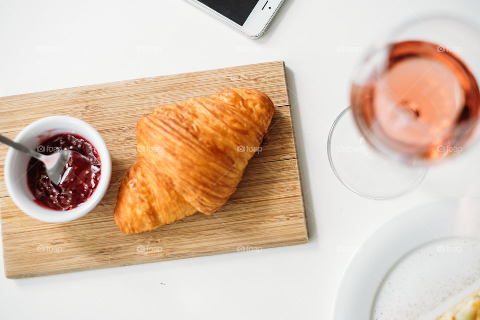 Croissant with jam and a glass of rose wine