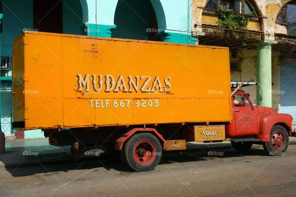 Old American truck parked in the street in front of colorful building representing classical architecture of Havana, Cuba on December 26, 2013.