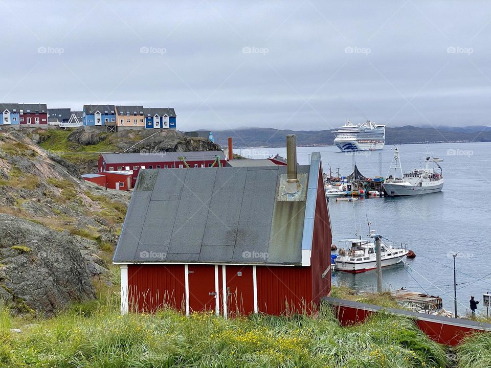 A small town in Greenland with boats and a cruise ship